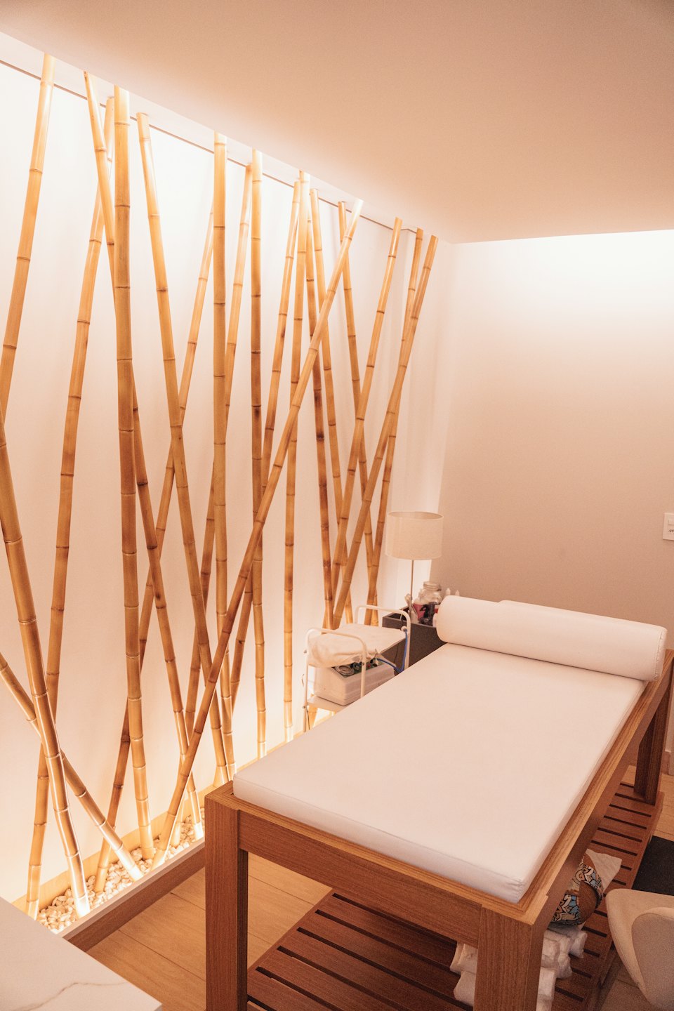Empty spa room with bamboo wall and massage table.