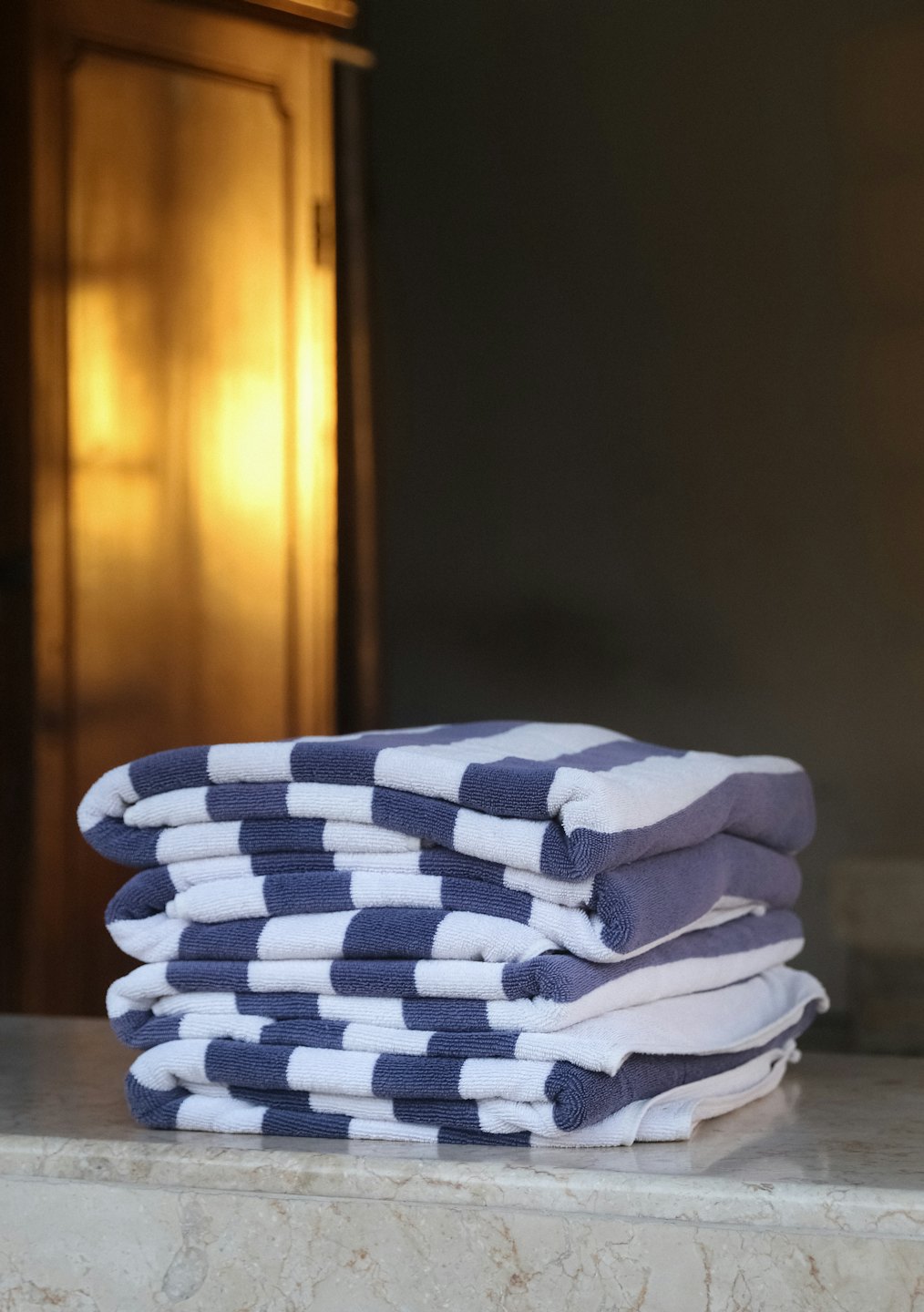 Neatly folded blue and white striped towels stacked on marble.